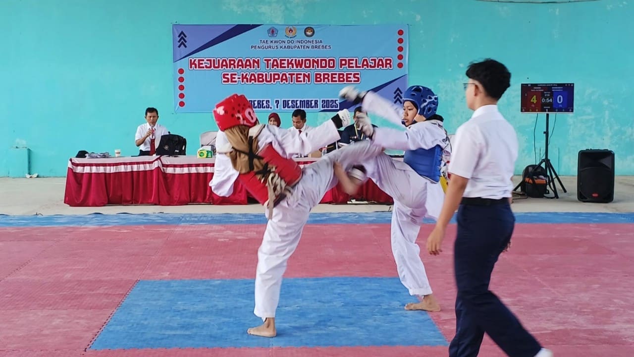 Dua atlet pelajar beraksi dalam kategori kyorugi (pertarungan) pada Kejuaraan Taekwondo Pelajar se-Kabupaten Brebes 2025 di GOR Pagojengan, Minggu (7/12/2025). Sebanyak 84 peserta dari SD hingga SMA/SMK berlaga mencari bibit unggul taekwondo Brebes. Foto: Portal Pantura/Yudhi Prasetyo