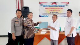 Ketua BPD Desa Tonjong Waryono (kiri) menyerahkan dokumen APBDes 2026 yang baru ditetapkan kepada Kepala Desa Samsudin di Kantor Desa Tonjong, Brebes, Rabu (14/1/2026) di gedung serba guna desa setempat. APBDes tahun ini mencatat penurunan Dana Desa hingga 69 persen dari Rp1,2 miliar menjadi Rp373 juta, sehingga pembangunan infrastruktur desa akan mengandalkan Bantuan Keuangan dari pokok pikiran anggota dewan. (Foto: Portal Pantura/Yudhi Prasetyo)